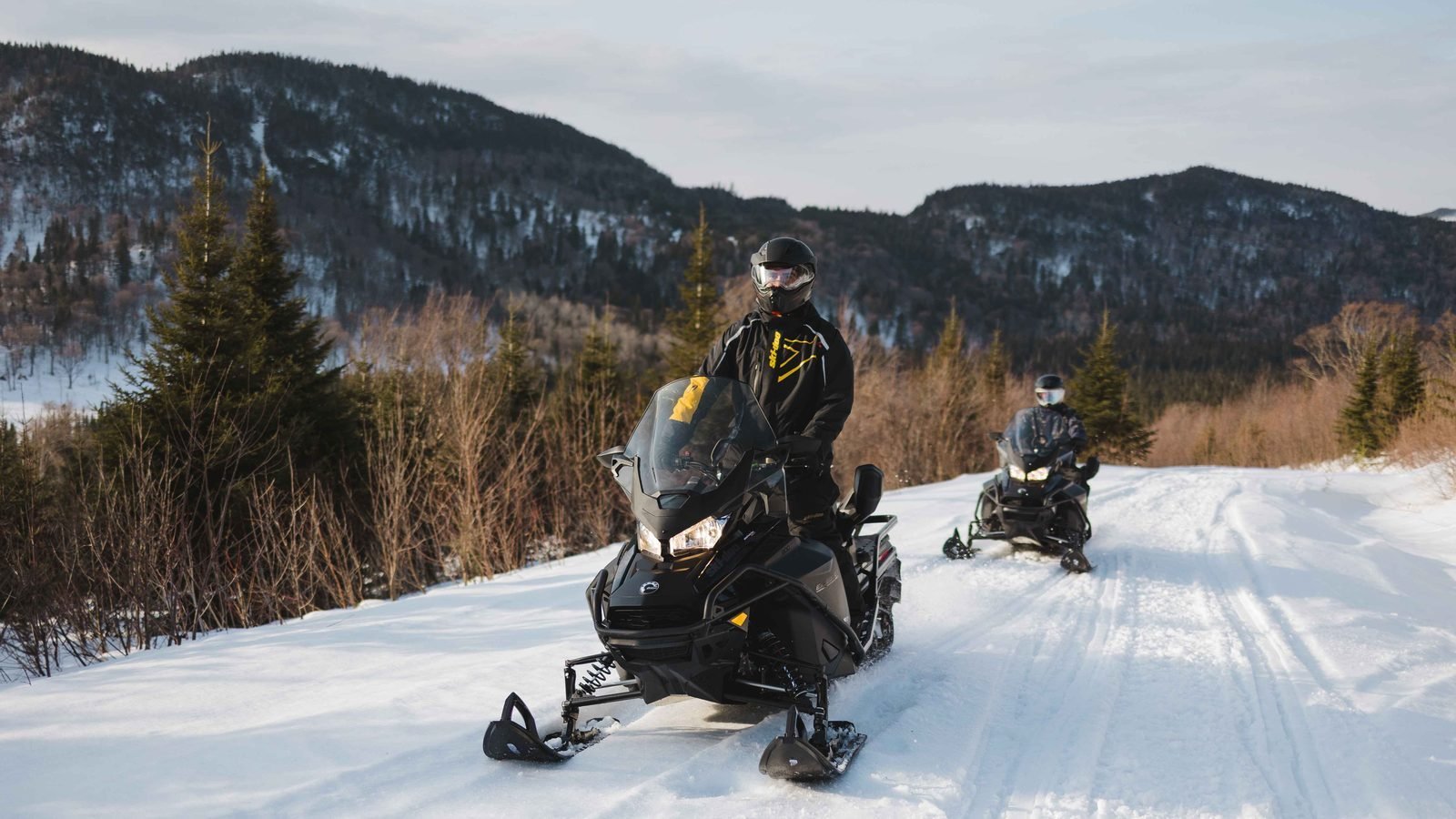 Deux motoneigistes en randonnée guidée sur un sentier de la Haute-Mauricie