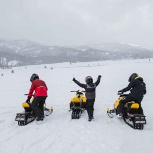 Trois motoneiges Ski-Doo arrêtées dans une grande vallée enneigée