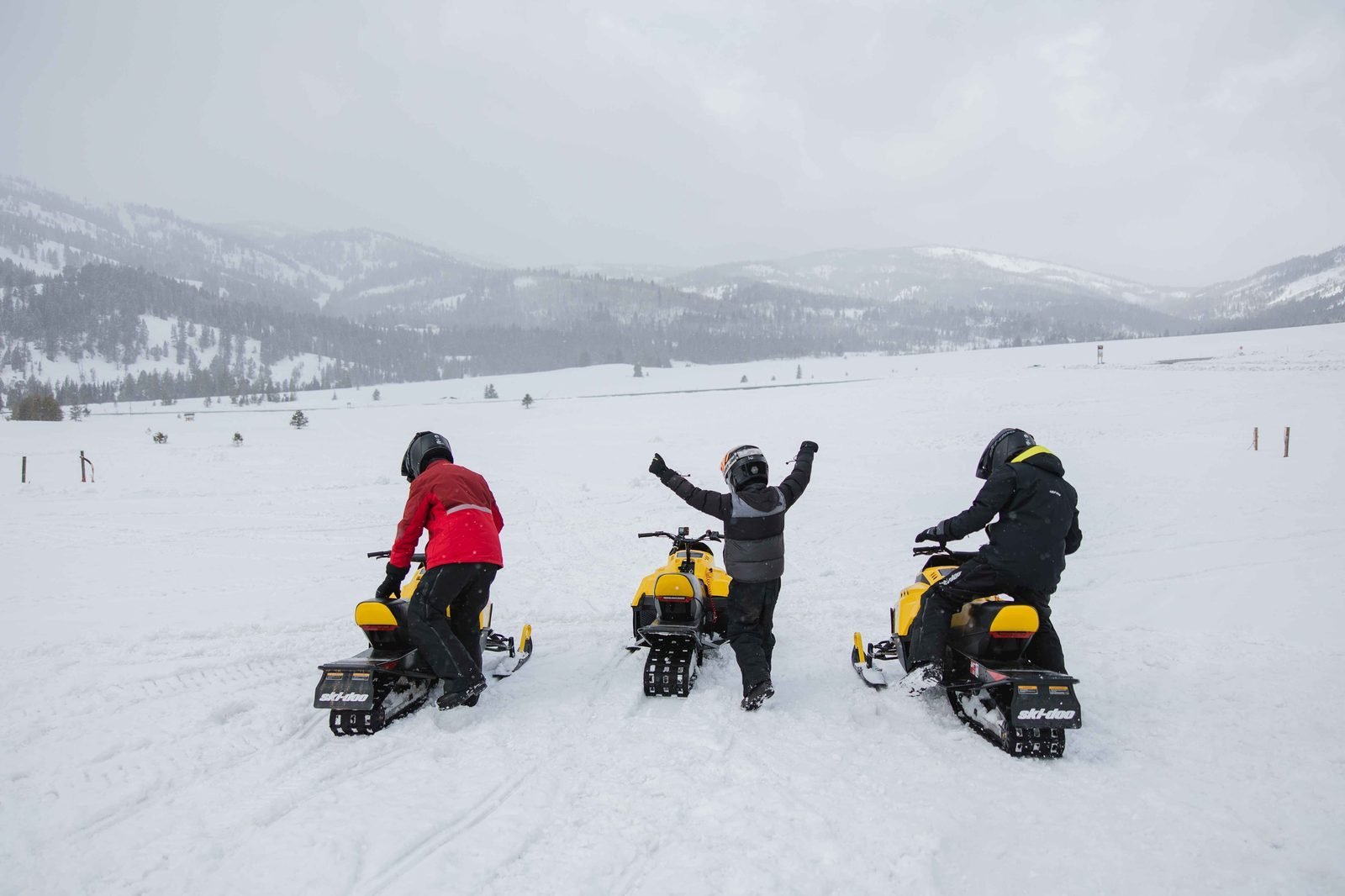 Trois motoneiges Ski-Doo arrêtées dans une grande vallée enneigée