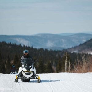 Motoneigiste sur un sentier surfacé devant les montagnes enneigées de la Haute-Mauricie