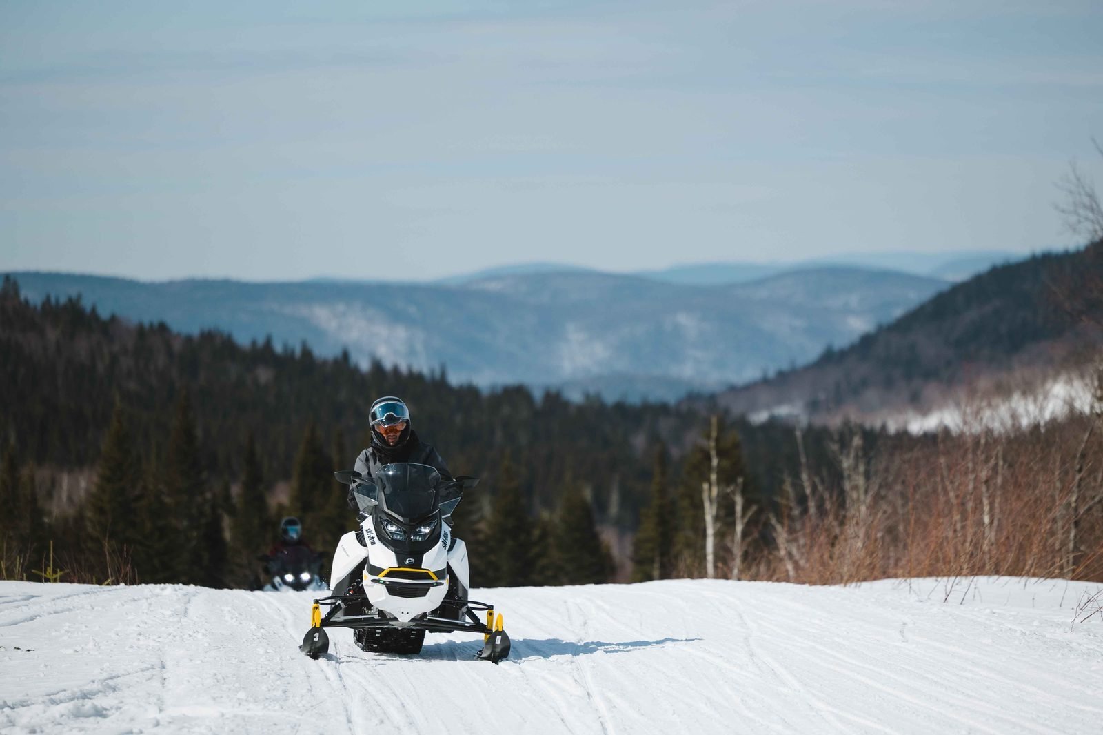 Motoneigiste sur un sentier surfacé devant les montagnes de la Haute-Mauricie